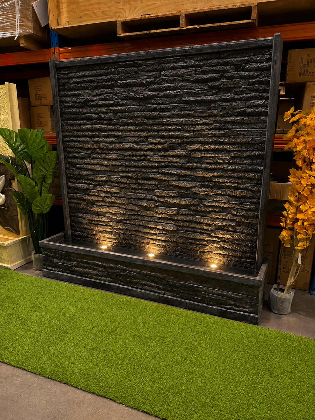 Eden granite look outdoor water wall with three warm base spotlights uplighting the stone curtain