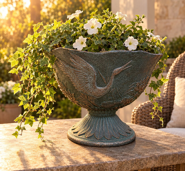Hacienda crane urn planter with trailing ivy and petunias on a stone patio table