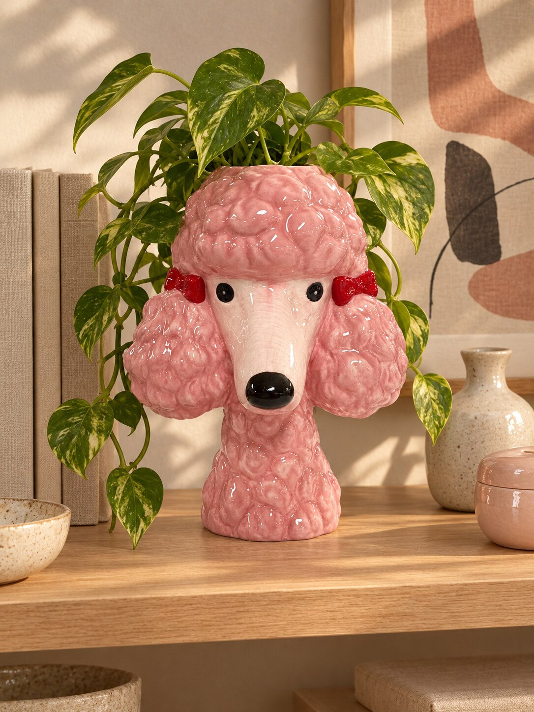 Benjita pink poodle head planter with trailing pothos on a timber shelf