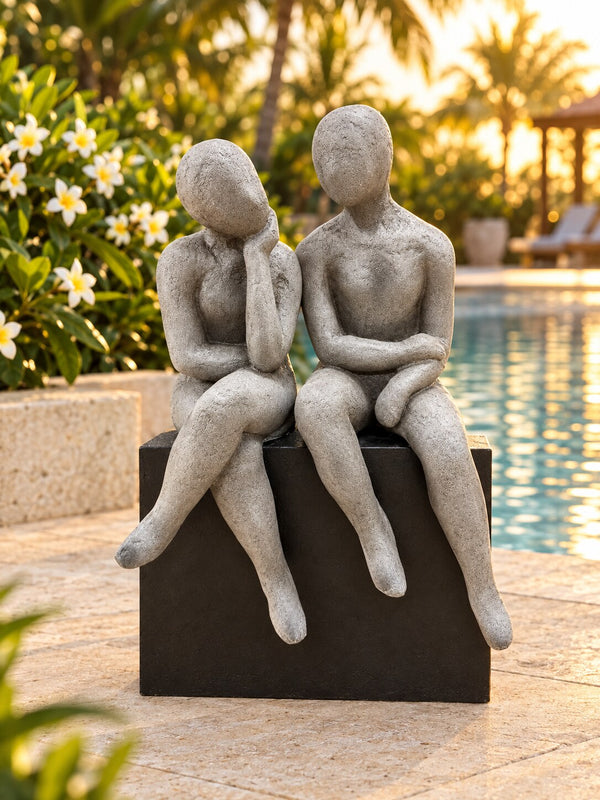 Gustaria grey and black seated figures sculpture beside a resort-style pool