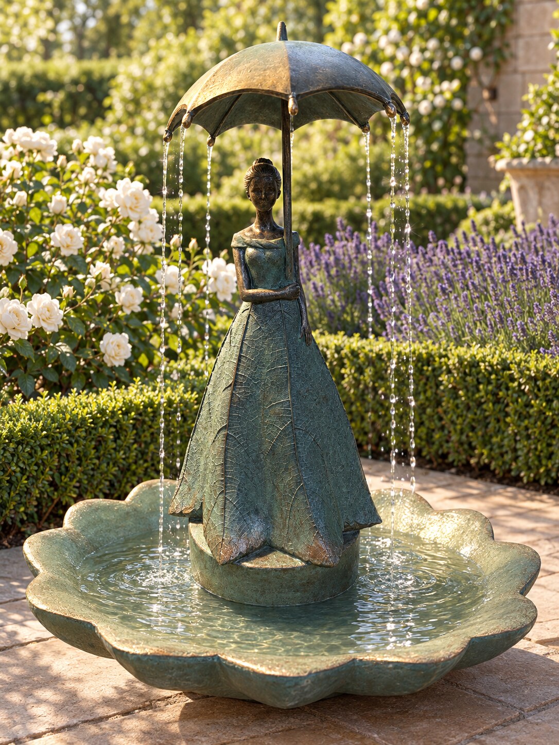 Paraguas resin lady holding umbrella fountain in verdigris on a garden terrace with roses and lavender