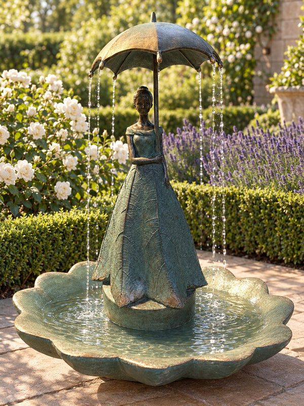Paraguas resin lady holding umbrella fountain in verdigris on a garden terrace with roses and lavender