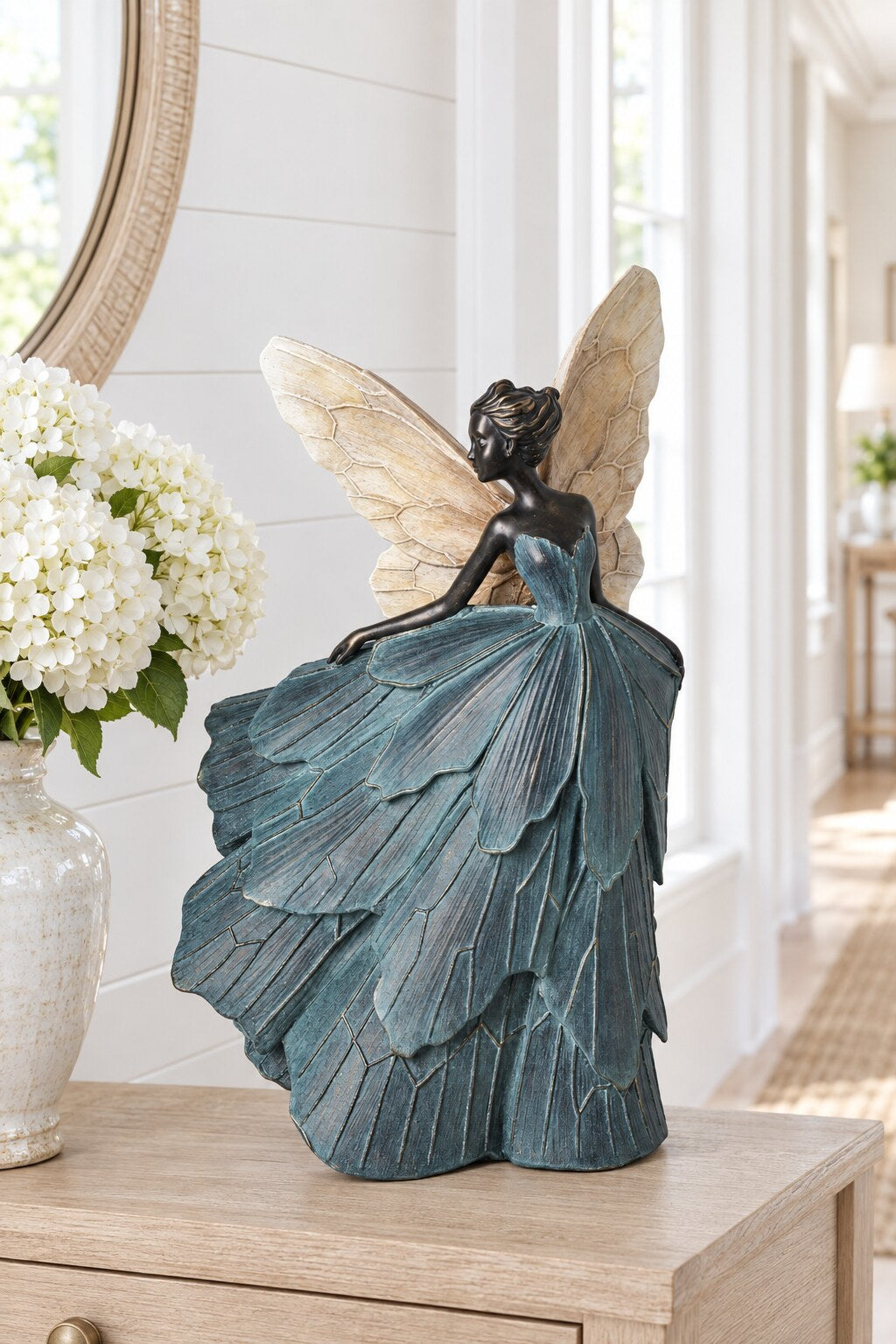 Teresa Blue Dress Girls fairy statue styled on a hallway console with white hydrangeas