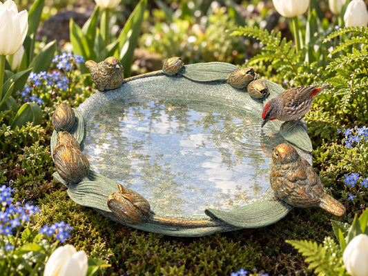 Volare verdigris resin bird bath with tulips and birds in a spring garden with a finch bathing